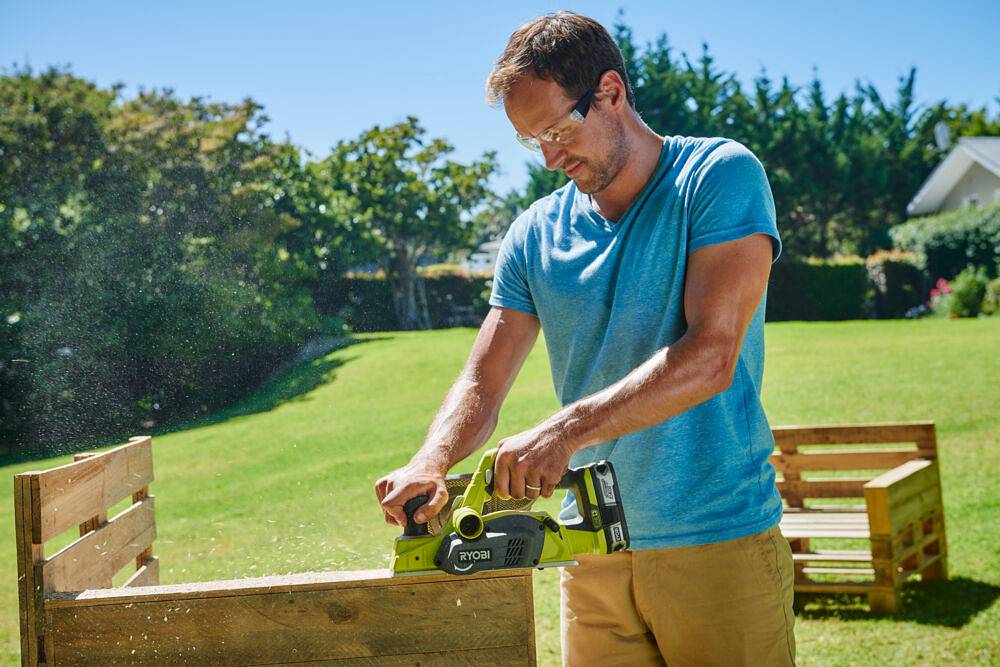 Mężczyzna w ogrodzie używa strugu akumulatorowego